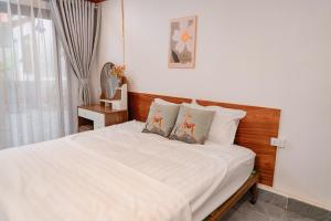 a bedroom with a bed with white sheets and a window at Dreamy Homestay in Xuân Sơn