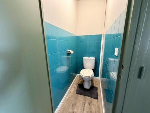 a bathroom with a toilet and a blue tiled wall at Appartement VAIS in Cognac