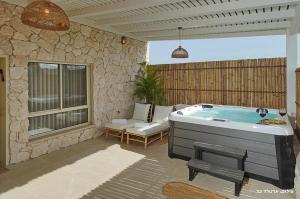 a jacuzzi tub in a patio with a bench at Shilo Boutiqe Suites in Mishmār Hāyardin