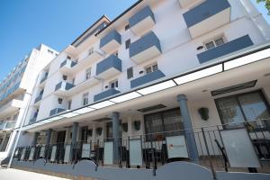 a white building with blue balconies on a street at Hotel Estense in Bellaria-Igea Marina