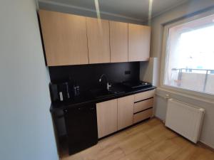 a kitchen with wooden cabinets and a sink and a window at Aparto 1 in Złotów