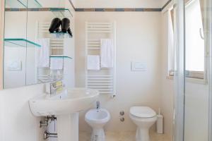 a white bathroom with a sink and a toilet at Nice villa only 100m from the beach in Fregene