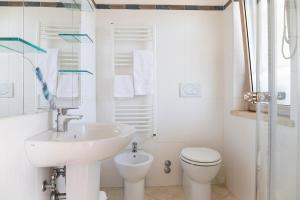 a white bathroom with a sink and a toilet at Nice villa only 100m from the beach in Fregene +32 photos