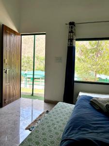 a bedroom with a bed and a large window at Stay Maasa Resort in Shivpuri