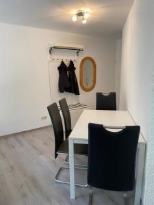 a dining room with a white table and black chairs at Am Wald, Am Berg in Unterreichenbach