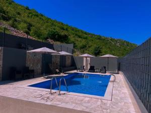 a swimming pool with umbrellas next to a hill at Villa Pietra in Stolac