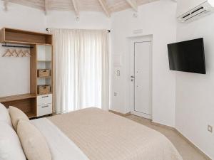 a white bedroom with a bed and a flat screen tv at Lux Studios With Private Pool by ILIOS Georgioupoli in Georgioupoli