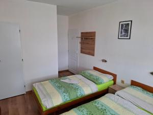two beds in a room with white walls and wooden floors at Penzion MAYKA in Hrabušice