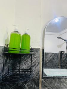 two green containers on a shelf next to a mirror at Tiba Meka Homestay in Komodo Labuan Bajo Airport