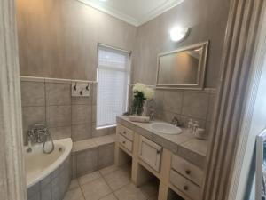 a bathroom with a tub and a sink and a bath tub at Villa Solace in Gordonʼs Bay +24 photos