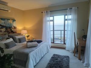a bedroom with a bed and a large window at Villa Solace in Gordonʼs Bay