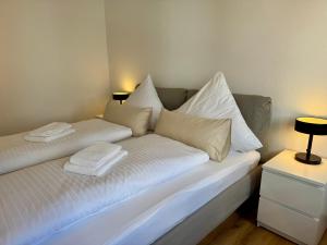 a white bed with white pillows on top of it at Apartment SeeZeit - Top Lage & nahe am Bodensee in Friedrichshafen