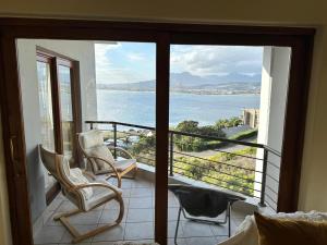 a balcony with two chairs and a view of the water at Villa Solace in Gordonʼs Bay