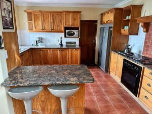 a kitchen with wooden cabinets and a granite counter top at Villa Solace in Gordonʼs Bay