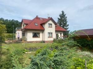 a house with a red roof in a yard at Domek pod Świerkiem in Wapnica