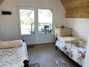 ein Schlafzimmer mit zwei Betten und einer Glasschiebetür in der Unterkunft Vikendice Ivanović in Prisoja