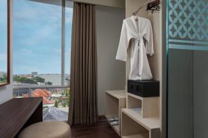 a hotel room with a robe hanging on the wall at Amandaru Hotel Pekalongan in Pekalongan