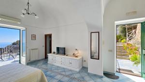 a bedroom with a bed and a tv and a balcony at Al Poggio Antico in Amalfi +24 photos