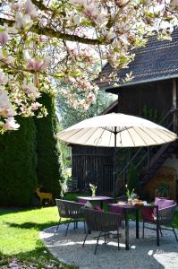 a table and chairs under an umbrella in a garden at Landhaus Riedl in Bad Füssing