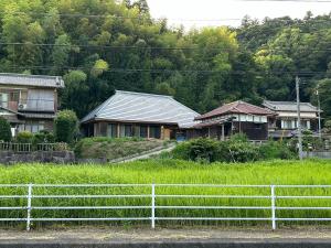 a group of houses in a field with a fence at 古民家宿 Mutsu Traditional Japanese House Inn MUTSU in Ōtaki