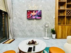 a living room with a table and a tv on a wall at Ruby Home Quy Nhon in Quy Nhon