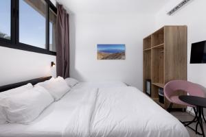 a bedroom with a white bed with a desk and a chair at Razin 37 in Eilat