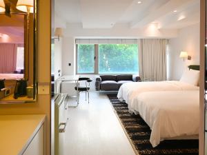 a hotel room with two beds and a couch at OOD Hotel Taipei DunhuaNorth in Taipei
