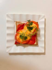 a white plate with a sandwich with fruit on it at The Avenue Hotel in Kogon