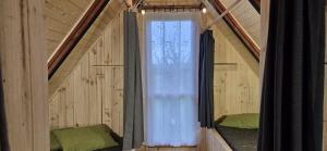 an attic room with a window and two beds at Folwark Pod Bukowcem in Podzamcze