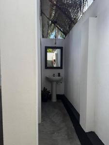 a bathroom with a sink in a white wall at Robbo's Surfcamp in Arugam Bay +8 photos