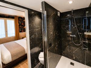 a bathroom with a shower and a toilet and a bed at Hôtel de Notre-Dame in Paris +38 photos