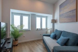 a living room with a blue couch and two windows at Cozy Oeiras Home for Beach, Lisbon & Cascais in Paço de Arcos