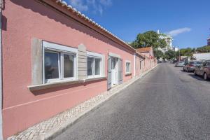 a pink building with windows on the side of a street at Cozy Oeiras Home for Beach, Lisbon & Cascais in Paço de Arcos