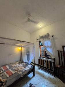 a bedroom with a bed with a canopy and a window at Robbo's Surfcamp in Arugam Bay