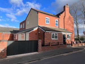 a brick house with a black gate on a street at The Limes! Flat 3 Private Studio Apartment in Quinton