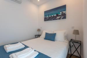 a bedroom with a white bed and a picture on the wall at Cozy Oeiras Home for Beach, Lisbon & Cascais in Paço de Arcos