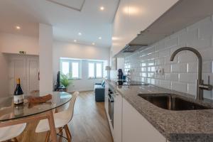 a kitchen with a sink and a table with chairs at Cozy Oeiras Home for Beach, Lisbon & Cascais in Paço de Arcos