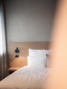 a bed with a wooden headboard and white pillows at Das Panorama Dependance in Caldaro