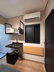 a small kitchen with a sink and a microwave at Studio Moderno e Prático Wi-Fi Rápido e AC in Ribeirão Preto