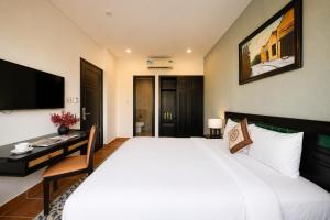 a bedroom with a large white bed and a desk at Nova Vista Villa Hoi An in An Bàn (2)