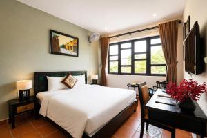 a bedroom with a white bed and a desk and a window at Nova Vista Villa Hoi An in An Bàn (2)