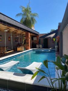 a swimming pool with white chairs and a building at Doña Emilia Hotel Boutique in Villarrica