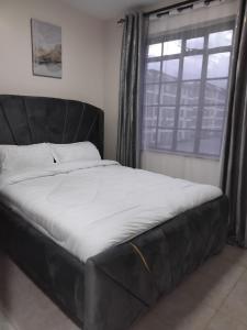 a black bed in a room with a window at Achievers stays in Kitengela 