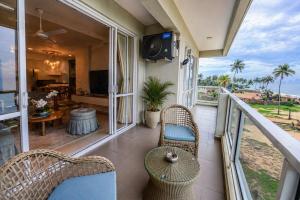 a balcony with wicker chairs and a table and a television at Anarma Oceanfront Apartment in Wattala