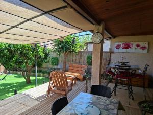 a patio with a clock and a table and chairs at Maison bord de mer a Cervione dans résidence Torra Mare à 20221 Prunete avec piscine collective copropriétaires et matériels de ventilateur dans toutes les pièces in Cervione