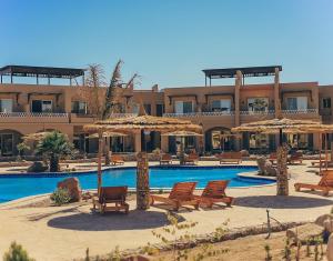 a resort with a swimming pool with chairs and umbrellas at Green studio in Dahab in Dahab