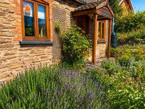 a stone house with a garden with purple flowers at Greytree Cottage in Ross on Wye