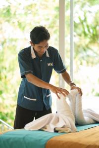 a woman in uniformtiestiesties tying a pillow on a bed at HeHa Waterfall Suites & Camping Ground in Paragajen +55 photos
