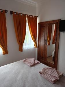 a bedroom with a bed with orange curtains and a mirror at Yükser Pansiyon in Side +34 photos