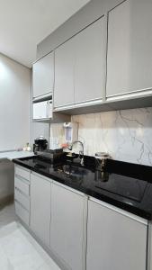 a kitchen with white cabinets and a black counter top at Residencial Felicita in Barueri +71 photos